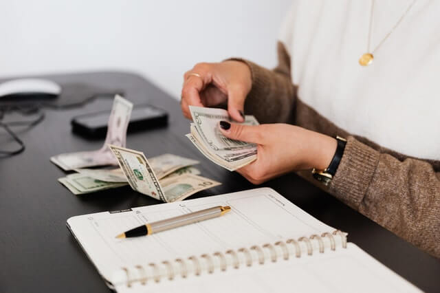 Services crop payroll clerk counting money while sitting at table